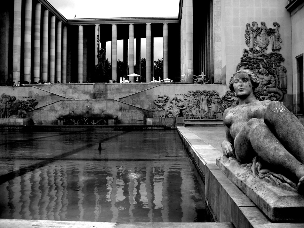 Schwarzweißfotografie einer steinernen Figur und ihrer Spiegelung im Wasser